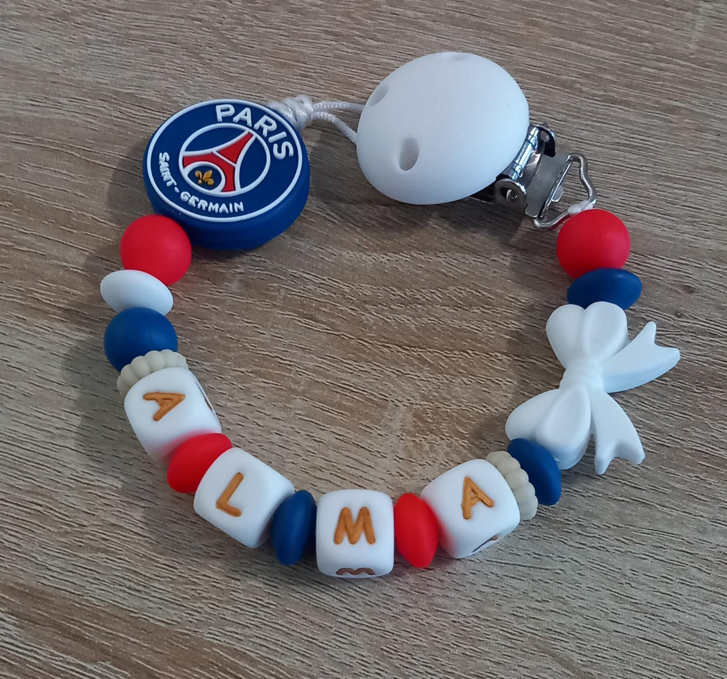 Attache tétine personnalisée Paris Saint Germain. Modèle Alma PSG pour fille. Cadeau naissance et jeunes parents. Création française.