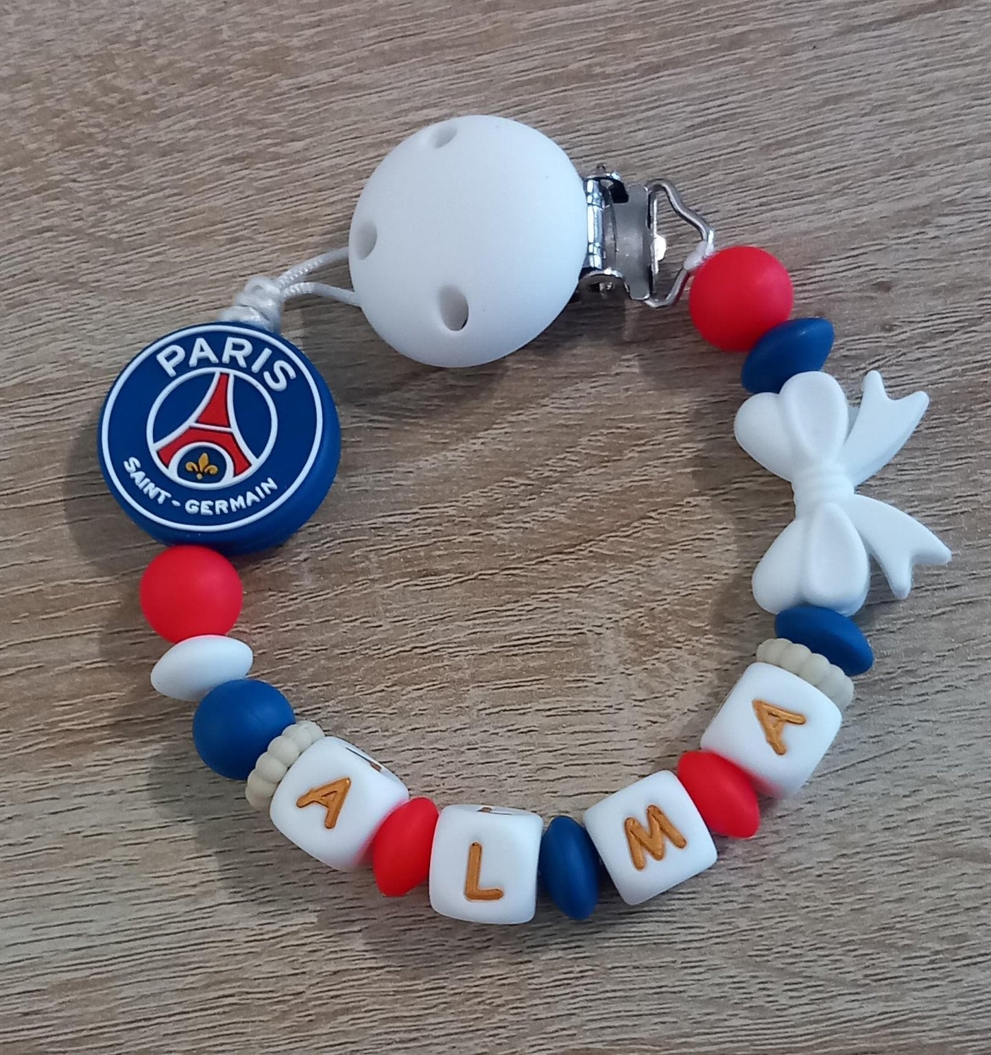 Attache tétine personnalisée Paris Saint Germain. Modèle Alma PSG pour fille. Cadeau naissance et jeunes parents. Création française.
