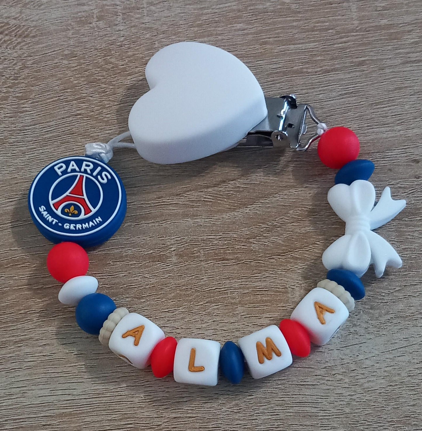 Attache tétine personnalisée Paris Saint Germain. Modèle Alma PSG pour fille. Cadeau naissance et jeunes parents. Création française.